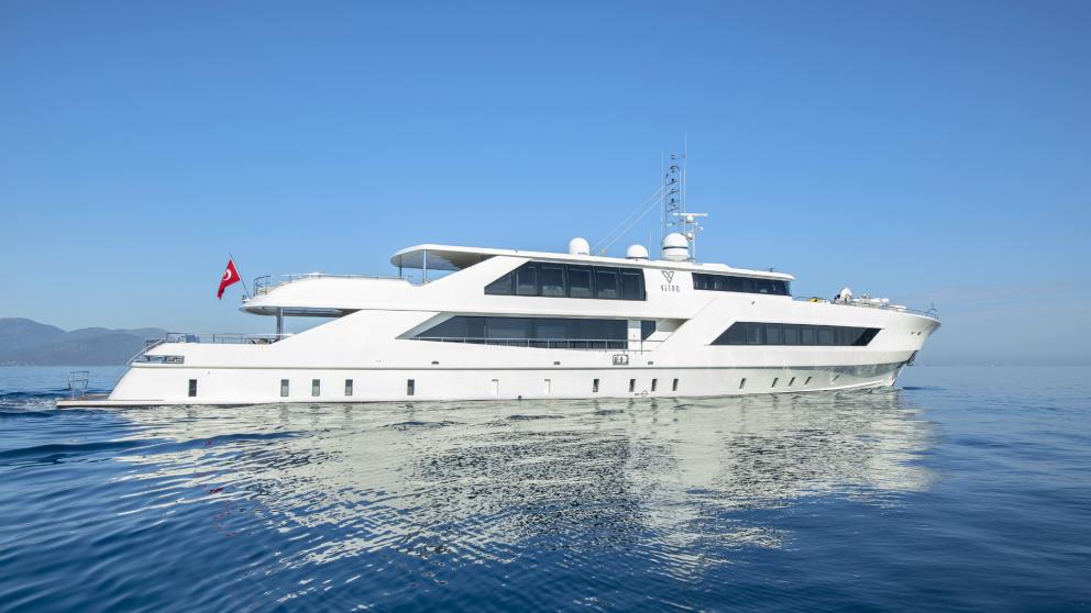 At the stern, the luxury yacht proudly displays the Turkish flag under a bright blue sky on the calm waters